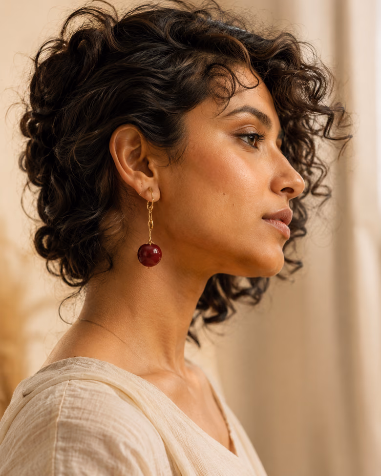 Woman in profile wearing deep red wine drop earrings.