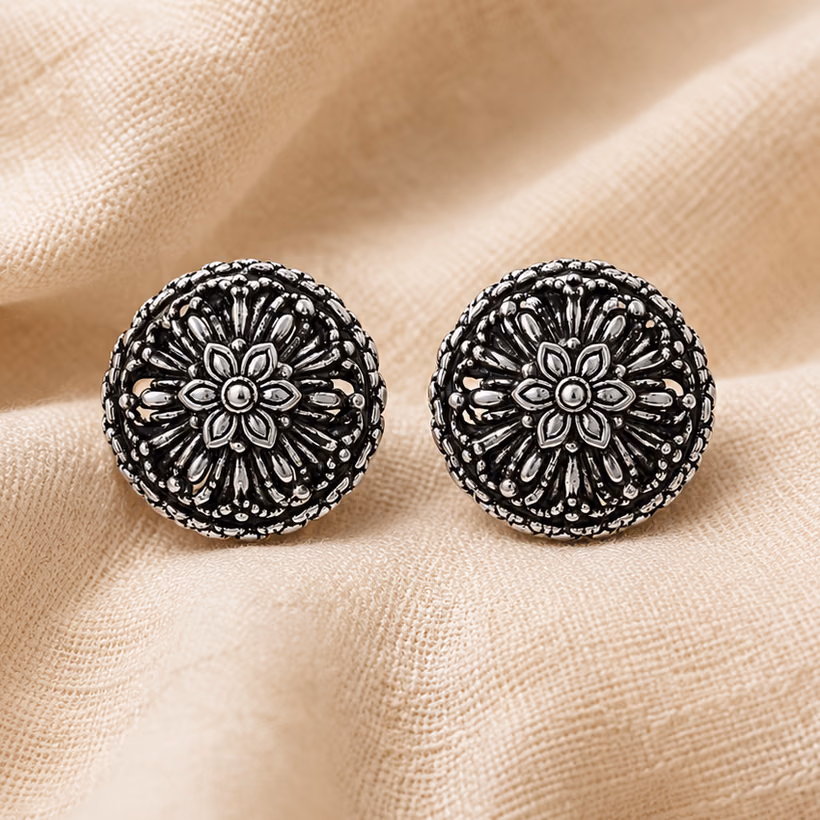 Oxidized silver floral stud earrings resting on linen.